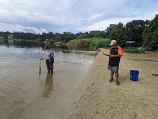 Two researchers collect samples on a beach