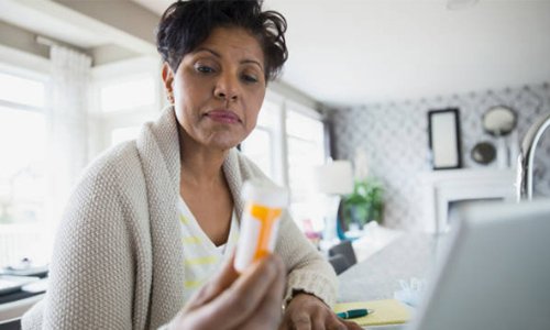 This is a picture of a woman looking at a bottle of medication