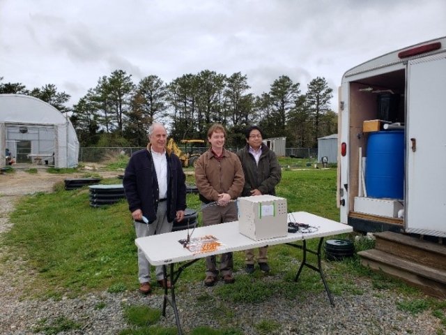 Dr. Qingzhi Zhu, Bud Dunbar, and Brian Feldman stand in front of their successful sensor at the Massachusetts Alternative Septic System Test Center. 